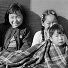 Photo de quatre enfants inuits assis ensemble par terre, Resolute Bay (Qausuittuq), Nunavut, septembre 1959