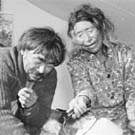 Photograph of an Inuit couple sitting in a tent. The woman is pouring water from a kettle into the man's tea cup, Eastern Arctic region, 1947