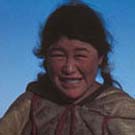 Photo d'une femme inuite debout dans la neige avec un groupe de chiens, Arviat (anciennement Eskimo Point), Nunavut, 1936