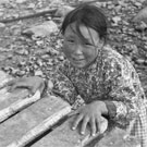 Photo de Maryann Tattuinee debout derrière une jetée, probablement à Coral Harbour, à l'Île Southampton, Nunavut, vers 1945-1946