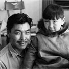 Photo d'un homme inuit, Kananginaq, tenant son fils sur ses genoux, lieu inconnu, Nunavut, 1968