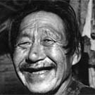 Photo d'un homme inuit souriant vêtu d'une chemise à carreaux, lieu inconnu Nunavut, vers les années 1950