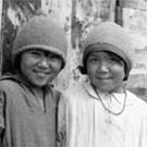 Photo de quatre enfants inuits debout devant une bâtisse, Lyon Inlet, Nunavut, 1933