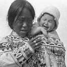 Photo d'une femme inuite portant un enfant qui pleure, lieu inconnu, Nunavut, vers 1926-1943