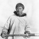 Photo de Memogana, un interprète inuit au service de la GRC, debout sur un quai et tenant en main un télescope, [Fullerton], Nunavut, vers 1904-1905