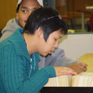 Photo de Corenna Nuyalia (à l'avant-plan) d'Iqaluit (anciennement Frobisher Bay) et Thomas Aggark (à l'arrière-plan) d'Arviat (anciennement Eskimo Point), des étudiants du programme de formation Nunavut Sivuniksavut effectuant des recherches dans les catalogues sur fiches à Bibliothèque et Archives Canada, octobre 2005