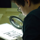 Photo de Jesse Mike, un résident d'Iqaluit, utilisant une loupe pour regarder des négatifs à Bibliothèque et Archives Canada, Ottawa, octobre 2005