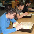 Photo d'étudiantes du programme de formation Nunavut Sivuniksavut effectuant des recherches dans les catalogues sur fiches à Bibliothèque et Archives Canada, Ottawa, novembre 2004. De gauche à droite: Nadia Mike-Dulmage et Jennie Soucie venant toutes deux de Iqaluit (anciennement Frobisher Bay) et Annie Aningmiuq de Pangnirtung (Pangnirtuuq)