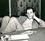 Photograph of Glenn Gould lounging beside a table, November 15, 1958