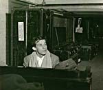 Photograph of Glenn Gould playing the piano backstage, with Philadelphia Orchestra trunks in the background